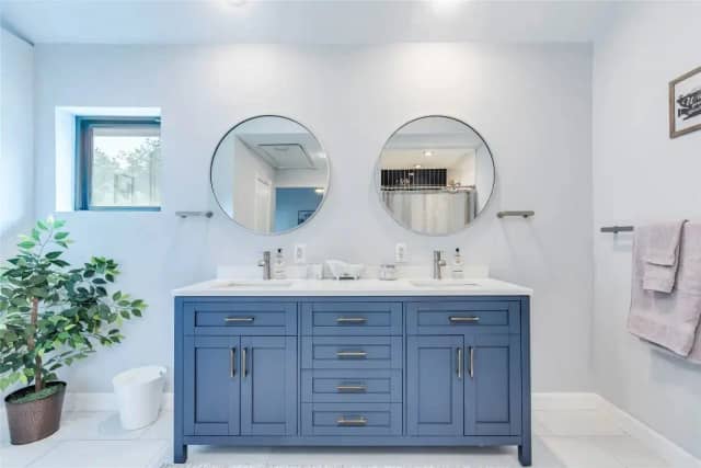 Bathroom with blue vanity and dual sinks